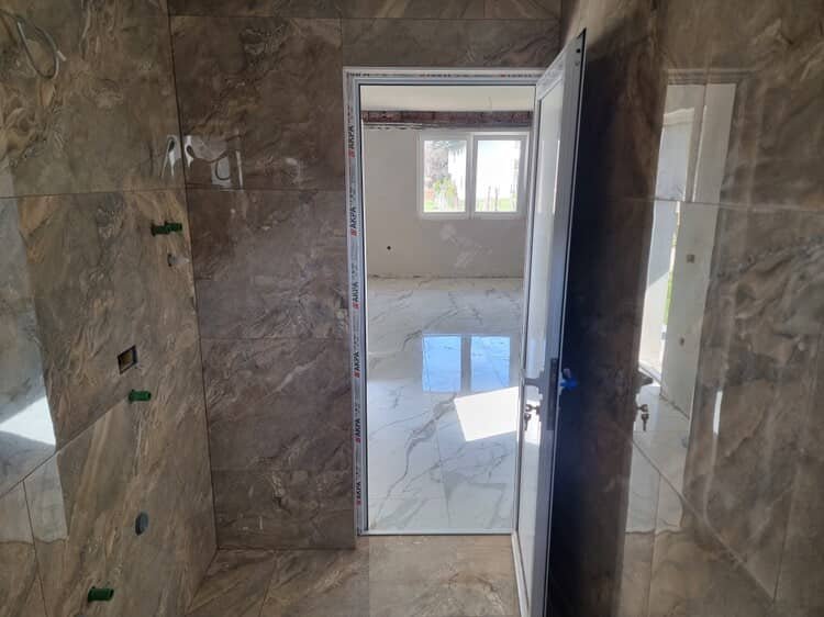 Kupatilo u izradi sa velikim tamnim keramičkim pločicama